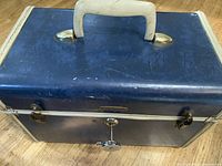 Top and front of Samsonite vintage travel case showing blue hard exterior, white trim, cream handle, and key lock