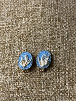 Front of clip-on earrings showing blue textured background and white coral design