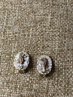 Pair of vintage 1950s clip-on earrings featuring gold-tone seahorse motifs on oval bases with white shell inlay and a faux pearl accent. Front view shows design details.