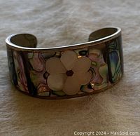 Clear close-up photo showing abalone shell inlay and mother of pearl flower on sterling silver cuff bracelet.