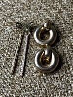 Two pairs of Erwin Pearl gold-tone earrings, one round hoop pair and one long bar pair, shown on a textured fabric surface.