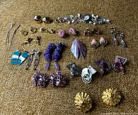 Full view of all jewelry items laid on a brown textured surface showing earrings in various colors and a watch bracelet with pastel charms.