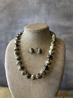 Front view of marbleized bead necklace and matching earrings on display bust showing bead pattern and gold spacer beads.