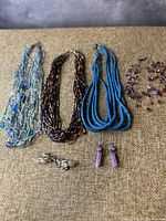 Overview of all beaded necklaces and earrings displayed on fabric background.