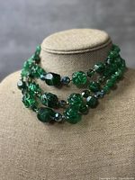 Front view of the chunky green beaded vintage necklace showing various bead shapes and textures on three strands.