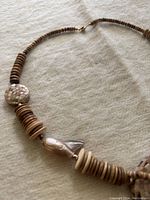 Full view of necklace laid out flat showing the abalone shell disc pendant and natural round beads along the strand.