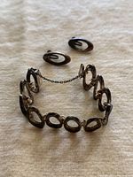 Photo of the bracelet laid flat showing connected open oval links and safety chain clasp