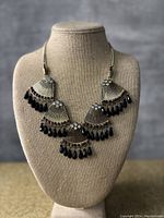 Full view of vintage fan-shaped necklace with five pendants adorned with black teardrop beads and small colored stones on a silver-tone chain.