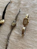 Photo showing three vintage gold filled wristwatches with various bands and rectangular or round faces.