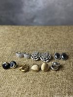 Top view of all six pairs of earrings arranged on a textured beige surface.