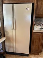 Full front view of a Whirlpool side-by-side refrigerator, cream/beige in color with vertical handles.
