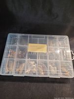 Closed transparent plastic organizer box with multiple compartments containing small plastic animal figurines individually wrapped in bags.