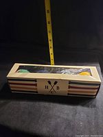 Box of six croquet balls with HBC logo and striped decorative pattern. Box window displays six balls in six colors.