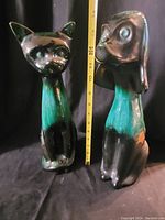 Photo of both Blue Mountain Pottery figurines, a cat and a dog, side by side with a measuring tape to show height.