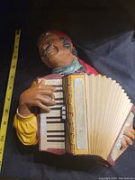 Side view showing the full accordion and upper body of the smiling man with a red headscarf playing the accordion.