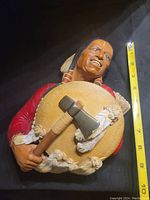 Front view of Bosson Native American warrior wall plaque showing full face and front details including shield and tomahawk, against dark background with measuring tape.