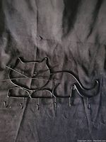 Metal wall hanger in shape of a cat showing distinct cat face with eyes and whiskers, and six hooks along the bottom.