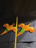 Pair of vintage chalkware pheasant plaques shown side by side with a measuring tape indicating width around 13 inches