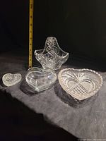 View of crystal basket and three heart-shaped glass pieces with measuring tape for size reference