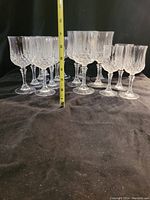 Photo showing 7 tall crystal wine glasses approximately 7 inches high with vertical and crosscut etched patterns.