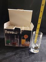 Set of six Favorit crystal shot glasses partially inside original box with one glass out and a measuring tape showing approx 3.5 inches height.