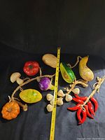 Vintage decorative food garland spread out on black surface showing all items and a measuring tape for scale.