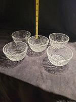 Set of five vintage glass dessert bowls arranged in a circle with a vertical measuring tape showing height approximately 2.5 inches.