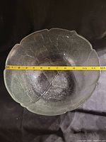 Top view of the large vintage glass bowl measuring about 11 inches in diameter with a measuring tape inside the bowl on a black background.