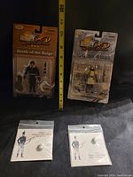 Two military figure packagings and two plastic sleeves with buttons, shown with measuring tape.