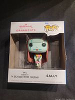 Front angle showing boxed Funko Pop! Hallmark Ornament Sally figure from The Nightmare Before Christmas with clear display window.