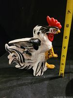 Side view of Japanese ceramic rooster figurine with measuring tape showing approximately 7 inches height