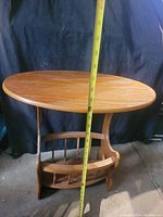 Photo showing the oval wooden table taken from the side with a tape measure showing the height measurement.