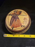 Top down view of the trinket dish showing the Greek warrior figure artwork and tape measure display of diameter around 5 inches.