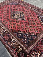 Full view of rug laid flat showing salmon pink field with geometric grid and central navy diamond motif