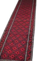 Full length view of Baluchi runner rug showing geometric pattern and borders in red, black, and white.