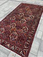 Full-length view of rug laid on stone floor showing overall field pattern and border edges.