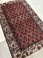 Top angled close-up showing the intricate hexagonal pattern and border of the red and white wool rug.