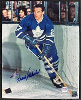 Color 8x10 action photo of Frank Mahovlich in full Toronto Maple Leafs uniform skating near boards, signed in blue ink with PSA certification label.