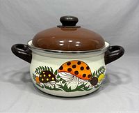 Front view of the vintage enamel mushroom design casserole pot with brown lid and handles