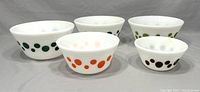 Five milk glass bowls with various colored polka dots visible, showing overall lot contents and size variations.