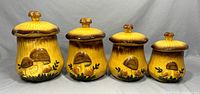 Front view showing all four ceramic canisters with lids, highlighting varying heights and mushroom motif.