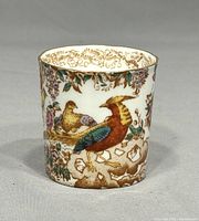 Porcelain cigarette holder decorated with colorful birds and floral motifs from Royal Crown Derby Olde Avesbury series, showing front angle with orange, green and blue bird.
