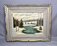 Framed vintage oil painting showing winter landscape with snowy trees and river, signed by L. Carmichael.