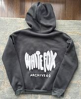 Back of the dark gray hoodie showing large white 'WHITE FOX ARCHIVE 6.0' graphic print.
