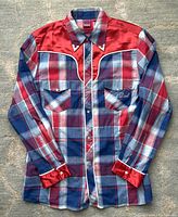 Full front view of men's plaid cowboy shirt with pearl snap buttons, metal collar tips, and color-block red yoke.