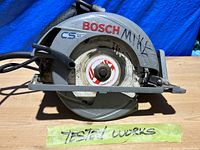 Side view of Bosch CS10 circular saw showing Bosch branding and sharpie name on faceplate along with 'Tested Works' tape.