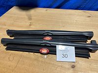 Two black Brica roller window shades with visible suction cup attachments and white hot temperature guide labels placed on a wood surface.