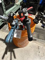 Orange 5 gallon Home Depot bucket filled with assorted caulking guns of different colors and designs.