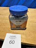 Full view of plastic jar with blue lid containing concrete screws, showing DuraDrive label and size information.