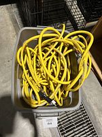 Photo of multiple yellow air hoses coiled inside a grey bin, showing hose ends with fittings.